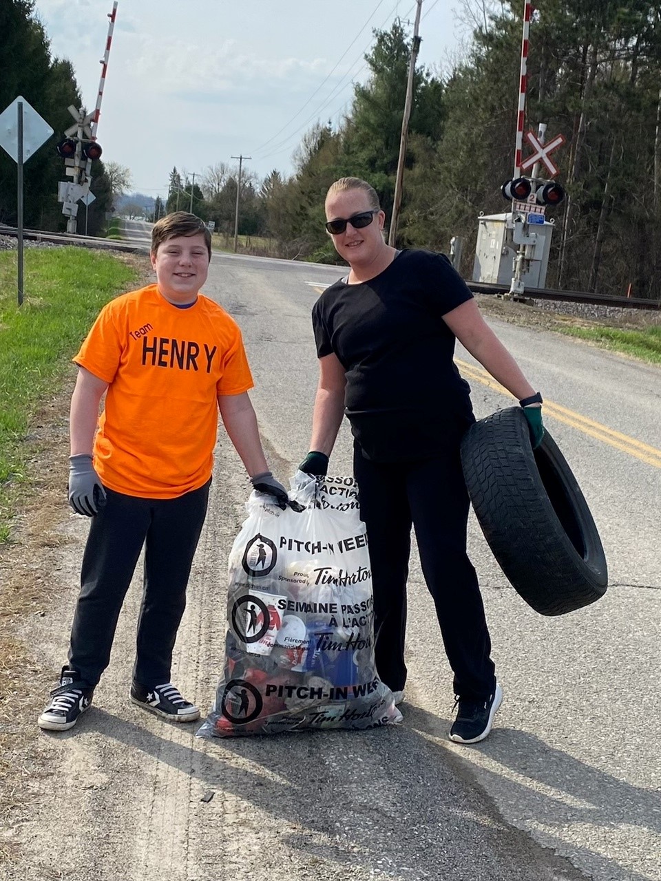 Councillor Henry and son holding an old tire and a bag of garbage